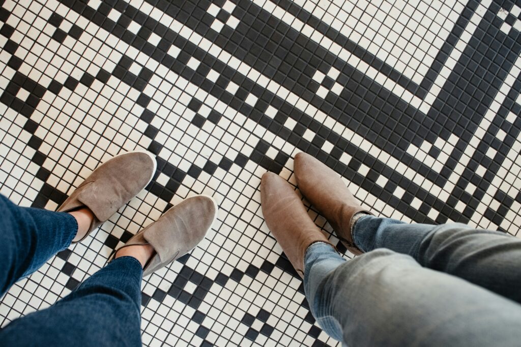 two people's feet standing on a black and white tile floor