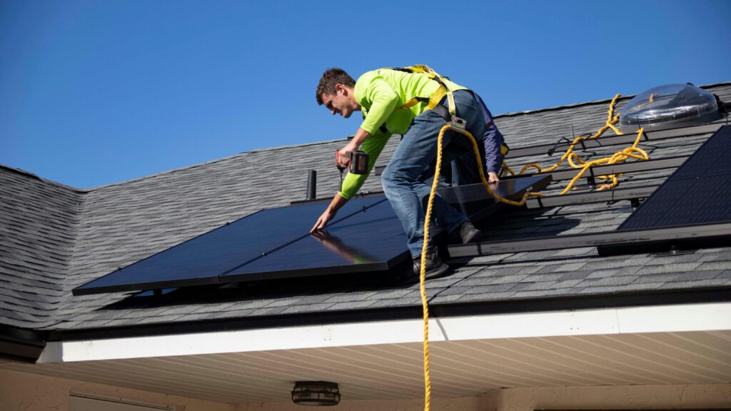 A man on a roof cleaning solar panels